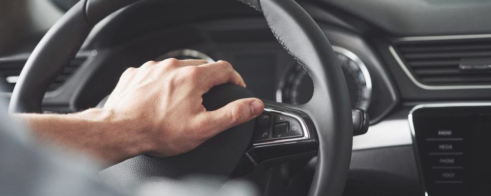 Man's big hands on a steering wheel while driving a car